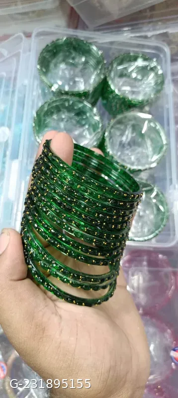 These green glass bangles feature a studded stone design and are often sold in sets of 12 for traditional occasions.