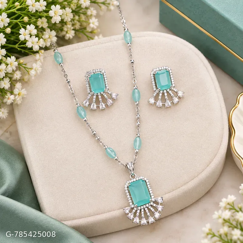 This is a silver-toned necklace and earring set featuring striking sea-green emerald-cut stones accented with sparkling cubic zirconia