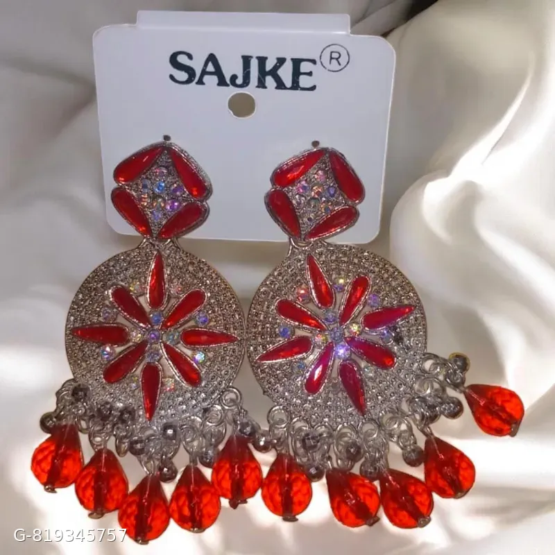 The image displays a pair of Sajke brand statement drop earrings featuring a sparkling crystal stud