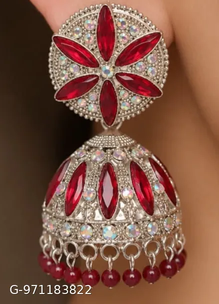 These silver-plated jhumka earrings feature a prominent floral design studded with red stones and smaller shimmering stones.