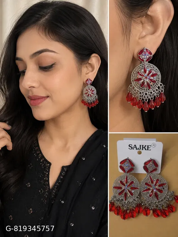 The image displays a pair of Sajke brand statement drop earrings featuring a sparkling crystal stud