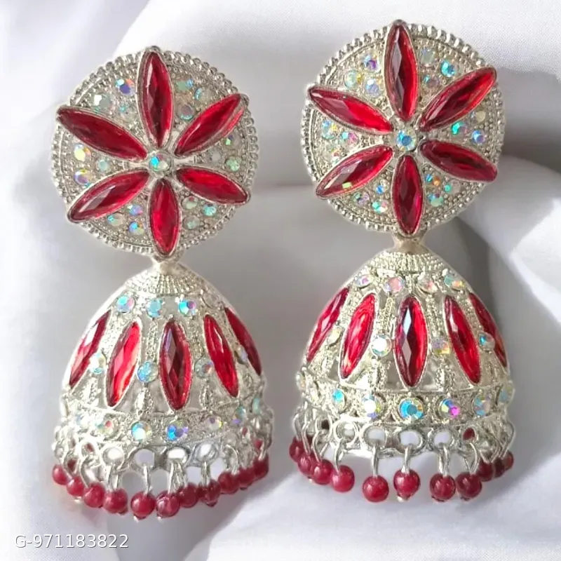 These silver-plated jhumka earrings feature a prominent floral design studded with red stones and smaller shimmering stones.